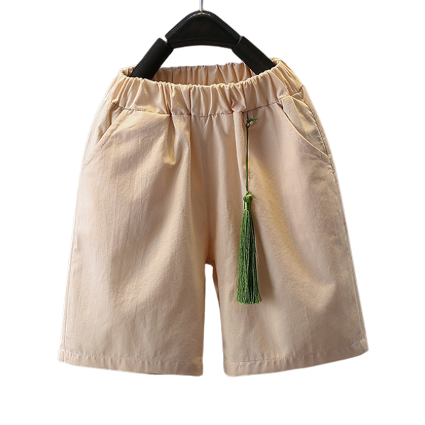Beige shorts with a green tassel on a hanger against a white background