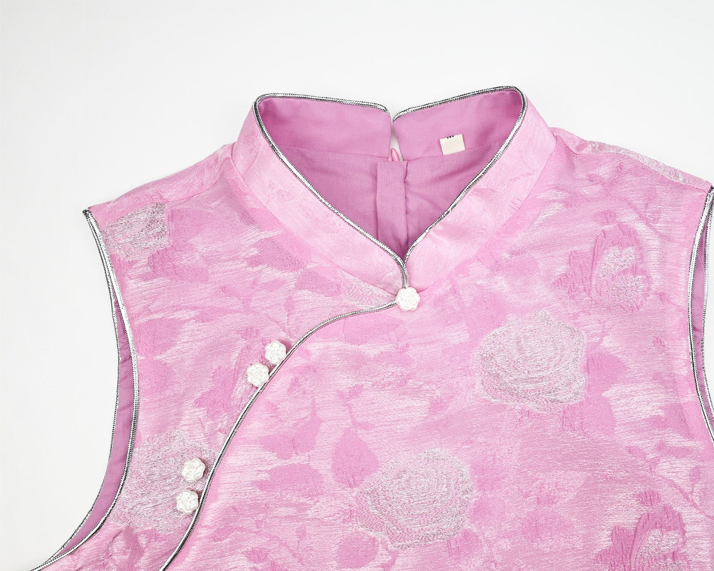Pink floral patterned vest with white buttons on a light gray background