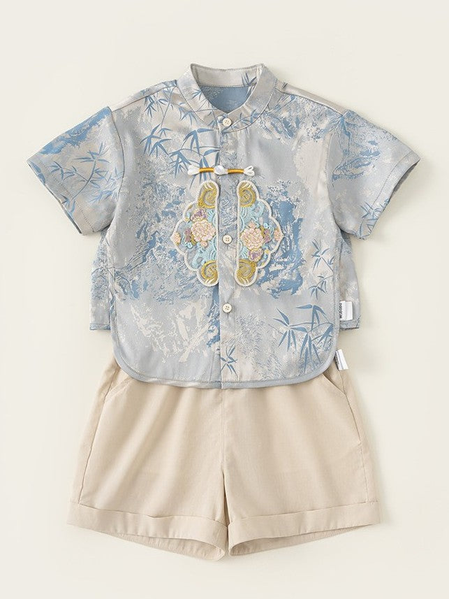 Children's outfit with floral shirt and beige shorts on a light background