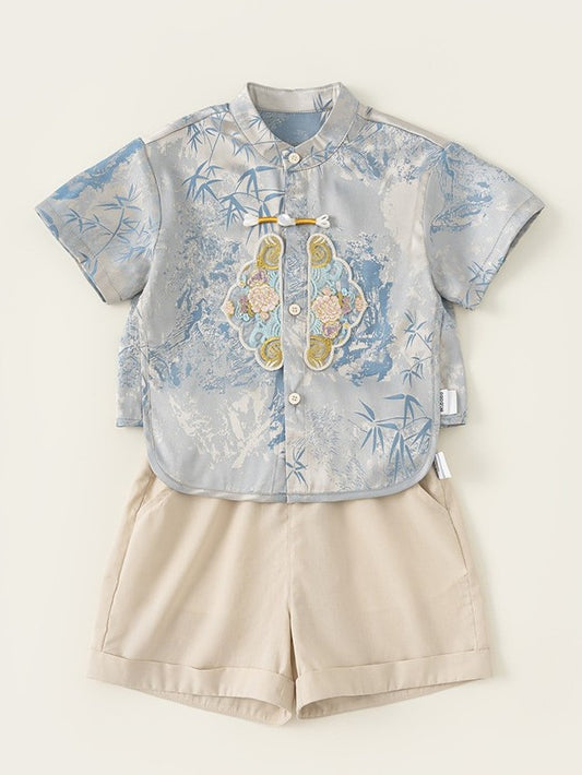 Children's outfit with floral shirt and beige shorts on a light background