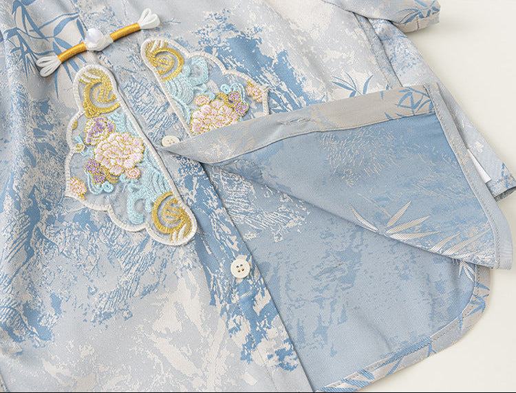 Light blue embroidered garment with floral patterns on a white background