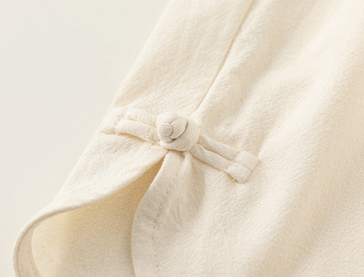 Close-up of a cream-colored garment with a button on a light background