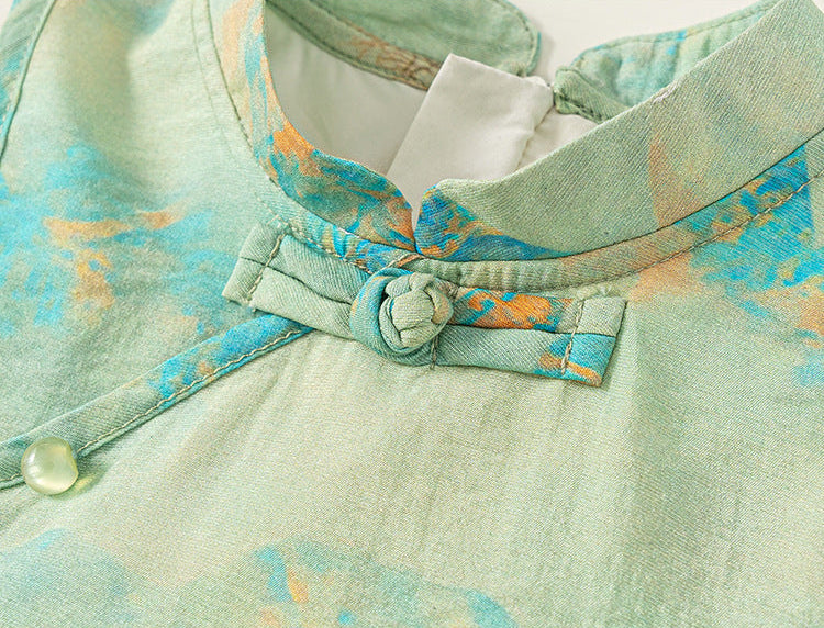 Close-up of a light green garment with floral patterns and a bow detail.