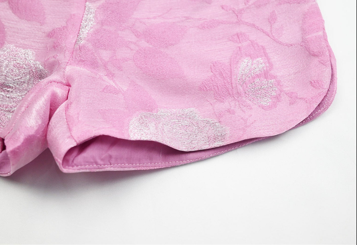 Pink fabric with silver floral patterns on a white background