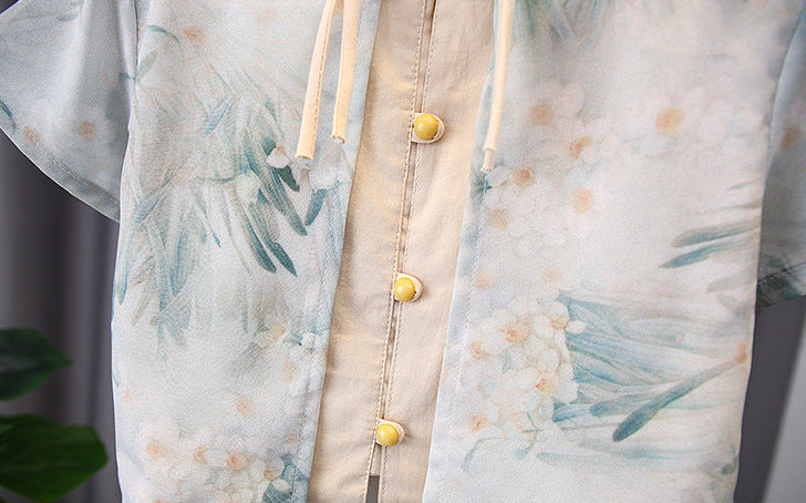 Light-colored shirt with floral pattern and yellow buttons on a plain background